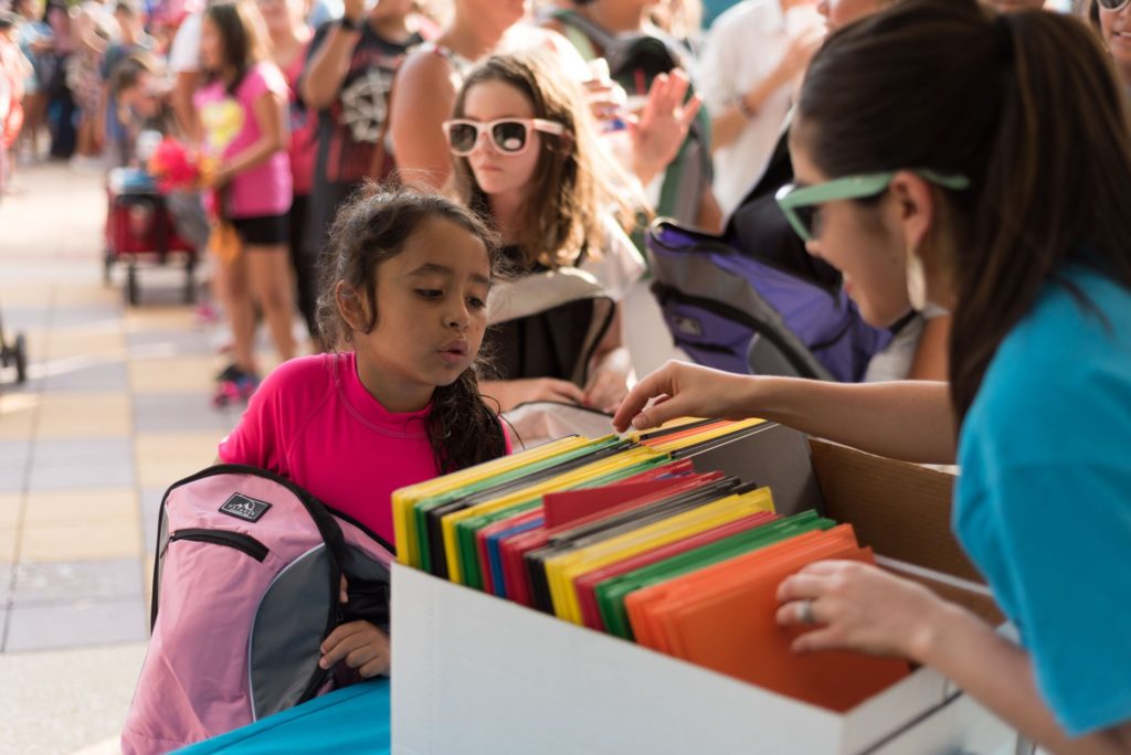 a young girl looks into a box of school supplies, as Gladys picks out which folder she would like.